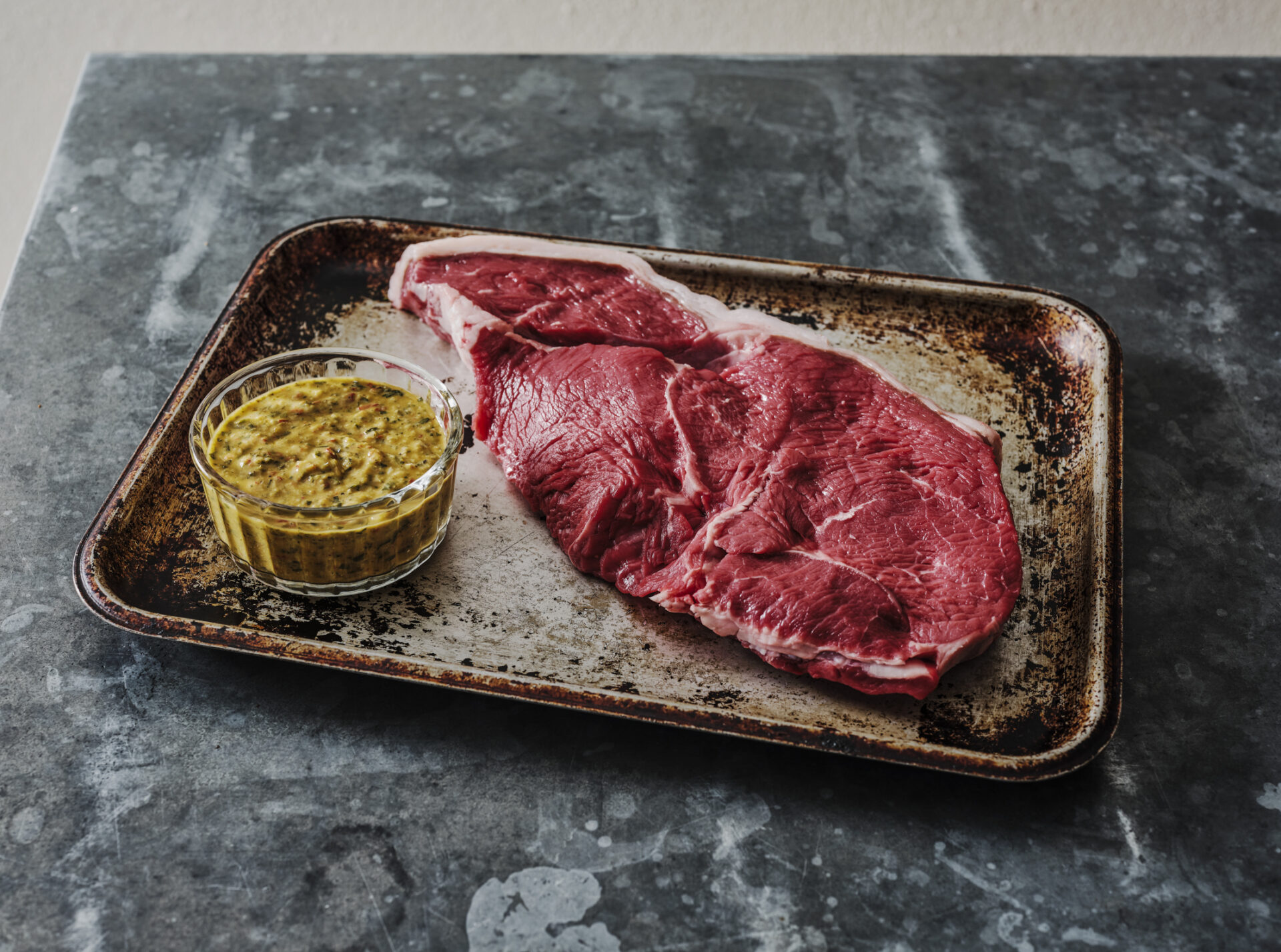 Juicy, dry aged sirloin steak on a tray with chimichurri sauce